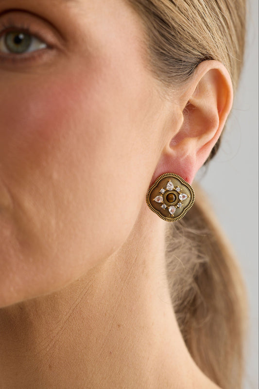 Close-up of a woman wearing a gold earring with a floral design.