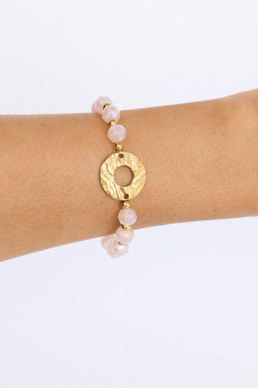 Model wearing Clarke Bracelet in pink with statement gold charm detail, angled on-wrist view on neutral background