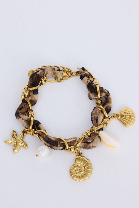 Model wearing Shelly Bracelet in leopard with mixed hanging charm detailing, angled on-wrist view on neutral background