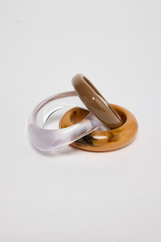Close-up of three resin bangles showing translucent lilac, taupe and mustard-amber marbled textures