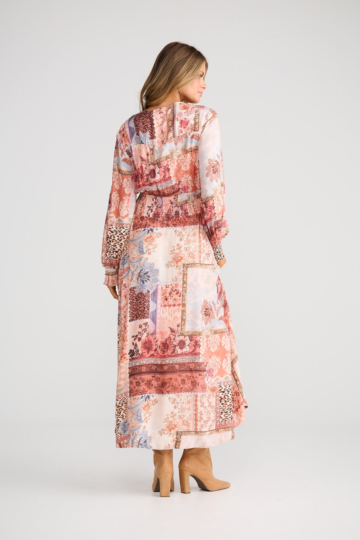 Woman wearing a long, patterned dress with a matching jacket on a white background