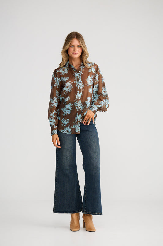 Woman wearing a floral blouse and jeans on a white background