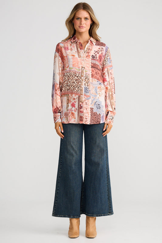 Woman wearing a patterned blouse and blue jeans on a white background