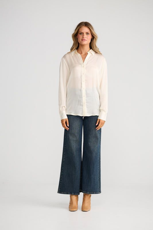 Woman wearing a white blouse and blue jeans on a white background