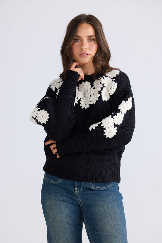 Model wearing Flower Child Knit in black and white with round neckline and extra wide cuffs, back view on white background
