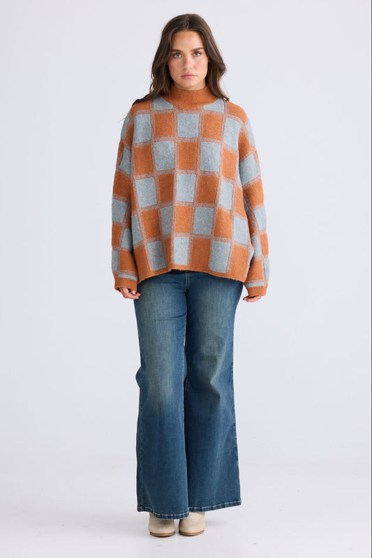 Model wearing Nyx Knit in teal and ochre with mock neck and dolman sleeve, side view on white background