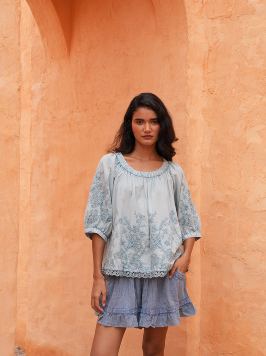 Thistle Top in powder blue with the Ithika Short, front view against a terracotta wall.
