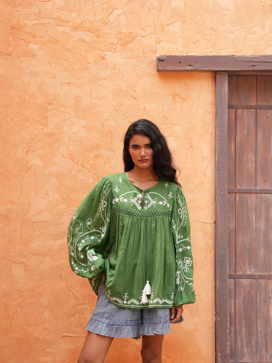 Sapphire Top in olive with the Ithika Short, front view against a terracotta wall.