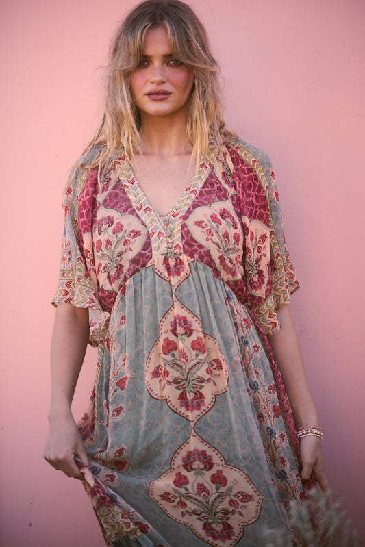 Tulara Dress in garden mist, close portrait against a pink wall.