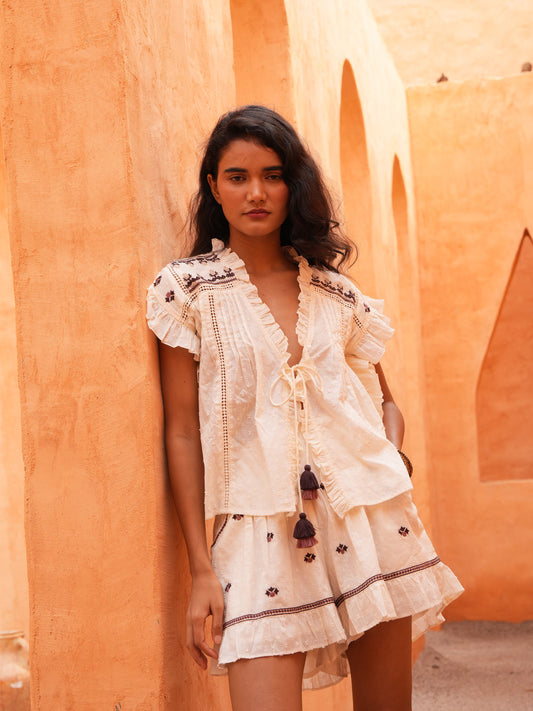 Saskia Short and Saskia Tie Top in natural dobby, leaning against a terracotta wall.