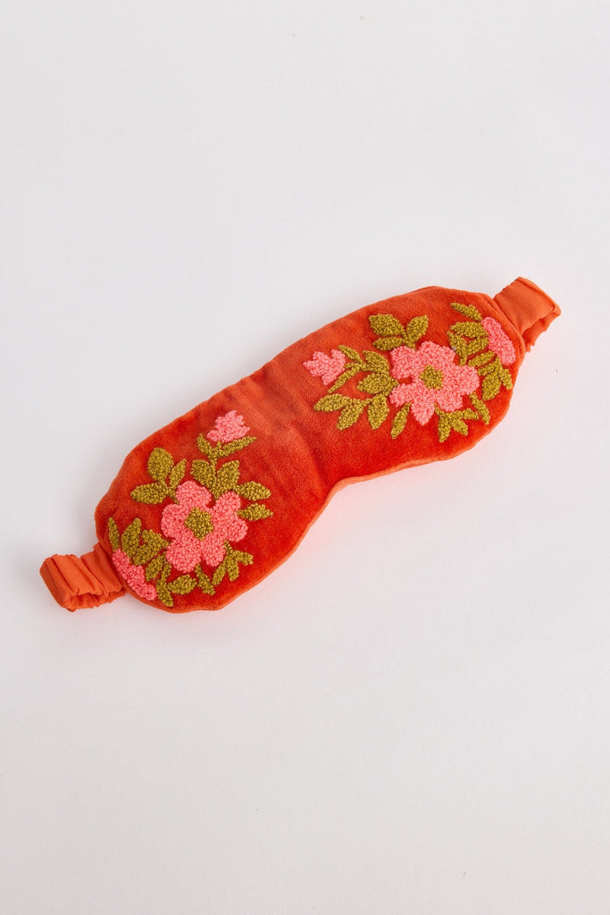 Red sleep mask with floral embroidery on a white background