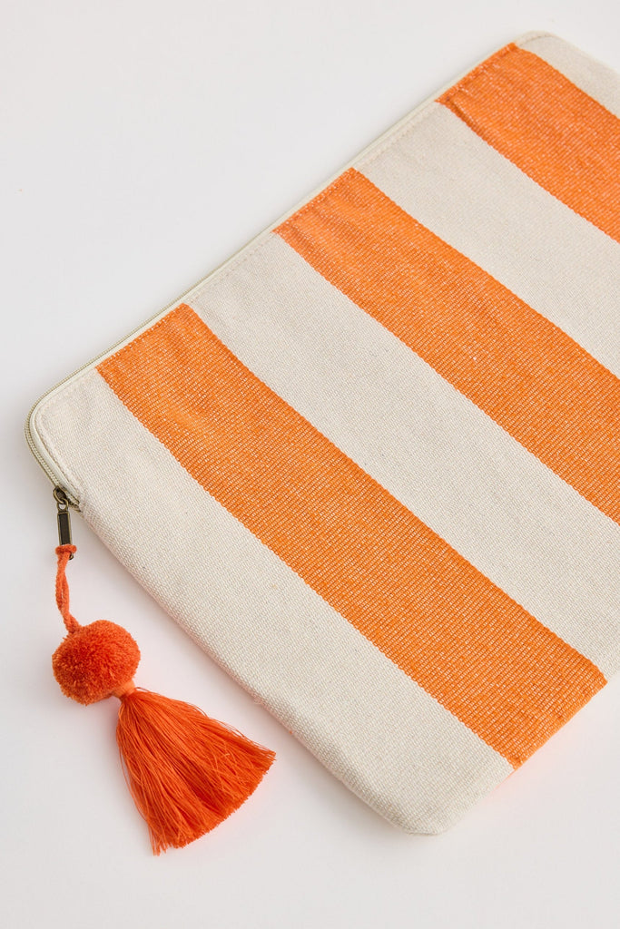 Striped pouch with orange and white pattern and tassel on a light gray background
