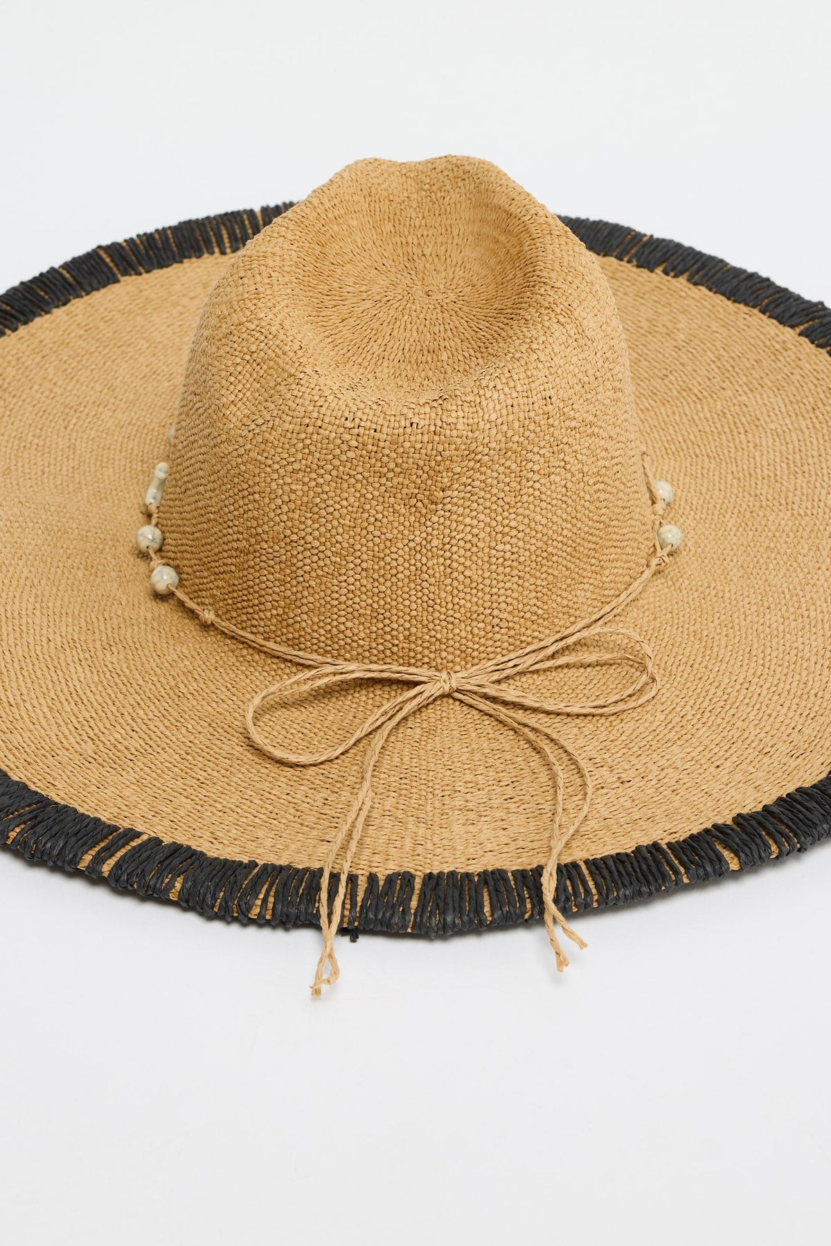 Close-up of the Carlitta Hat's woven texture, black fringed brim trim and beaded raffia tie