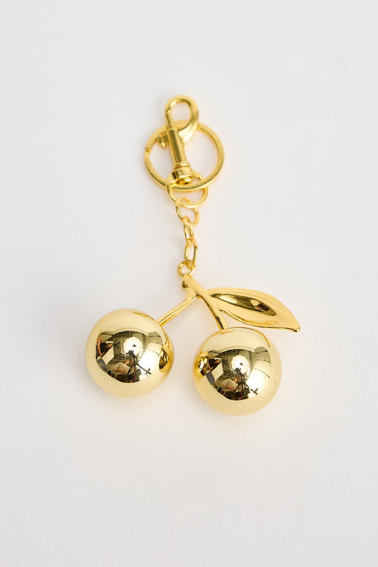 Gold cherry-shaped keychain on a white background