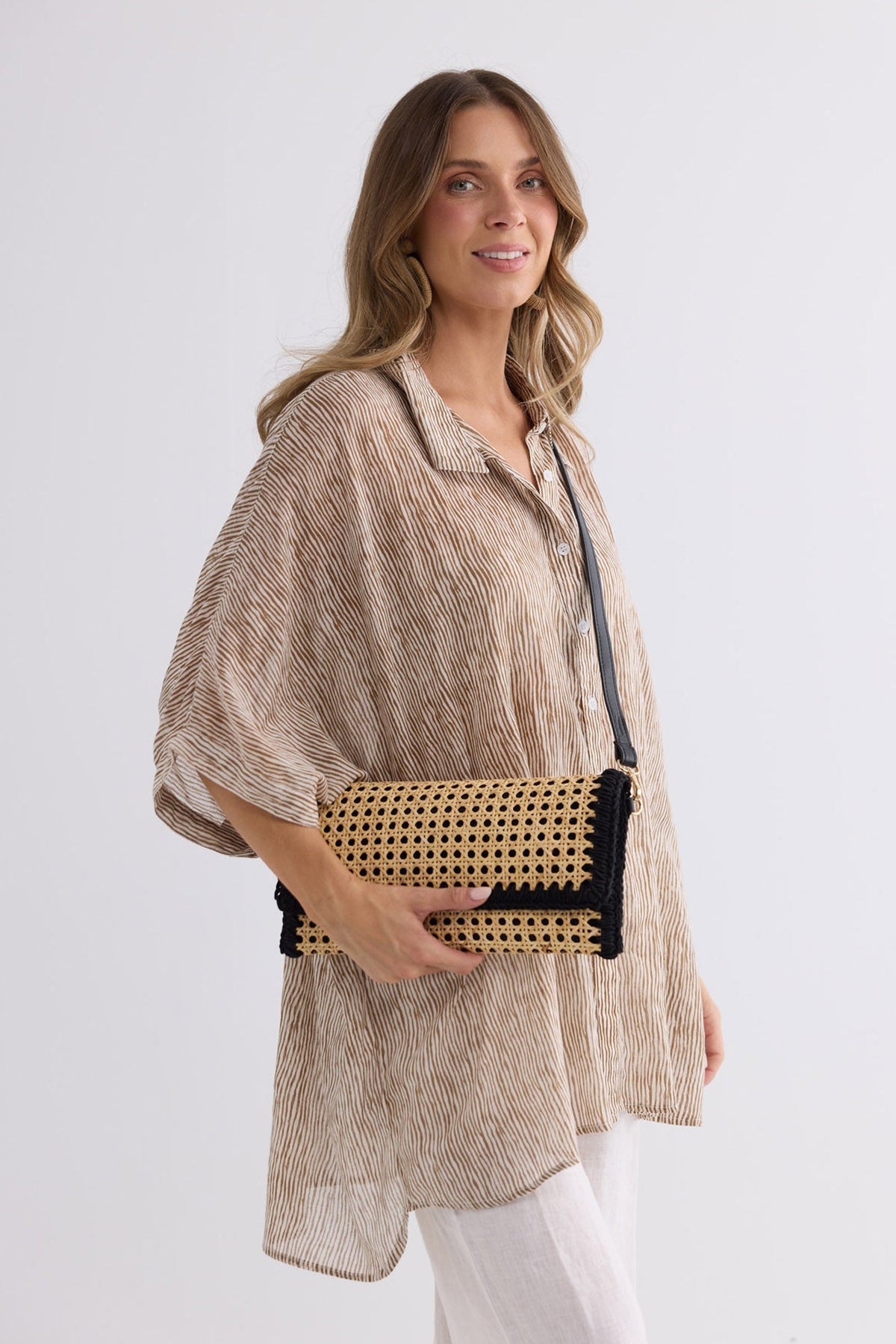 Reema Bag in black worn crossbody, side view over a striped outfit