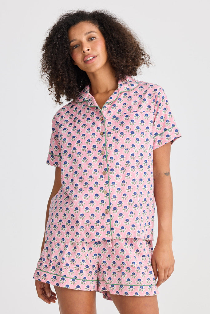 Woman wearing a pink floral pajama set on a white background