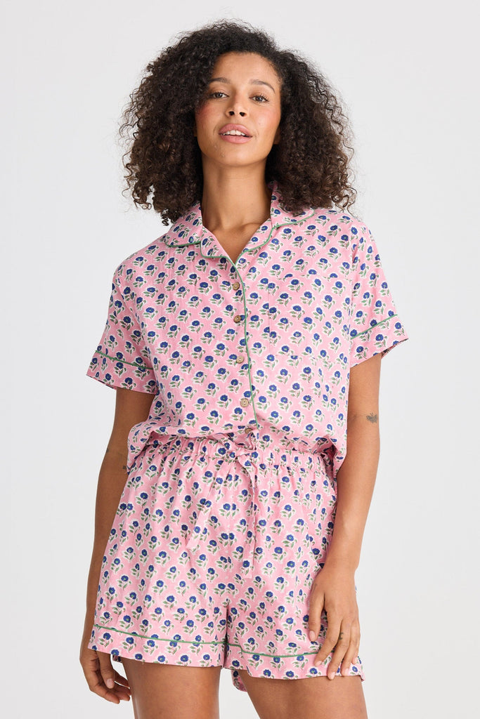 Woman wearing a pink floral pyjama set on a white background