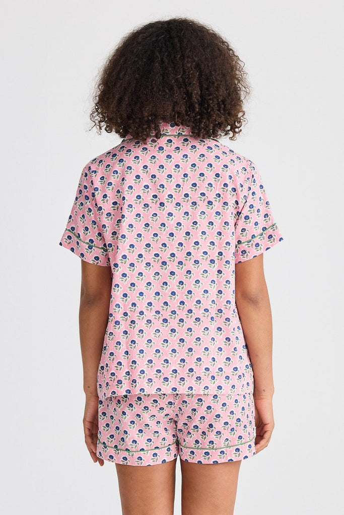 Person wearing a pink patterned pajama set on a white background