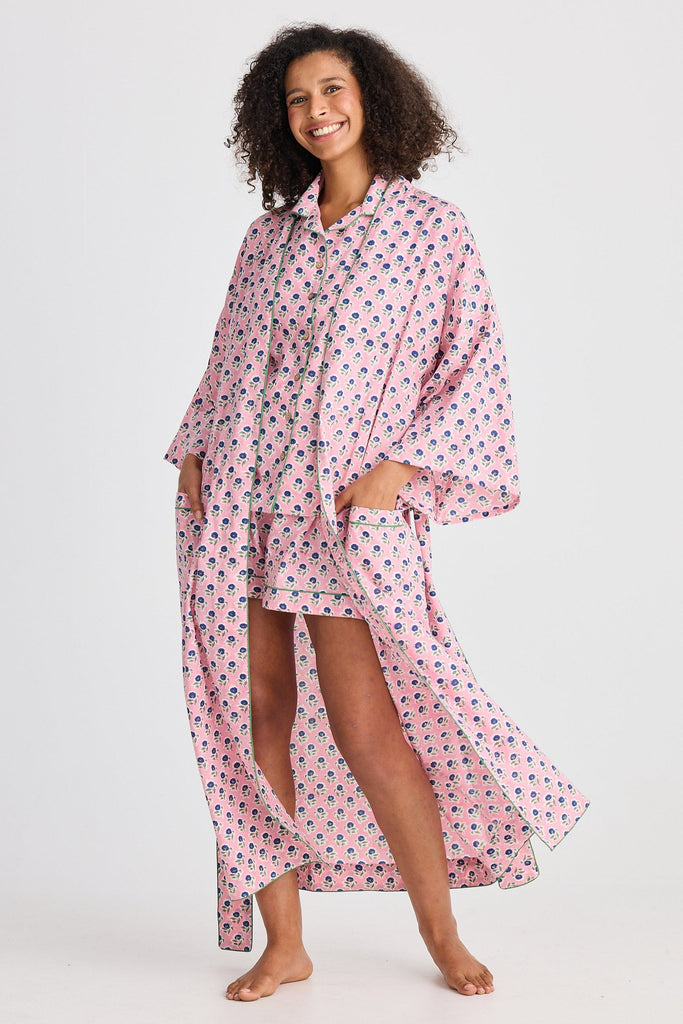 Woman wearing a pink floral robe and pyjama set on a white background
