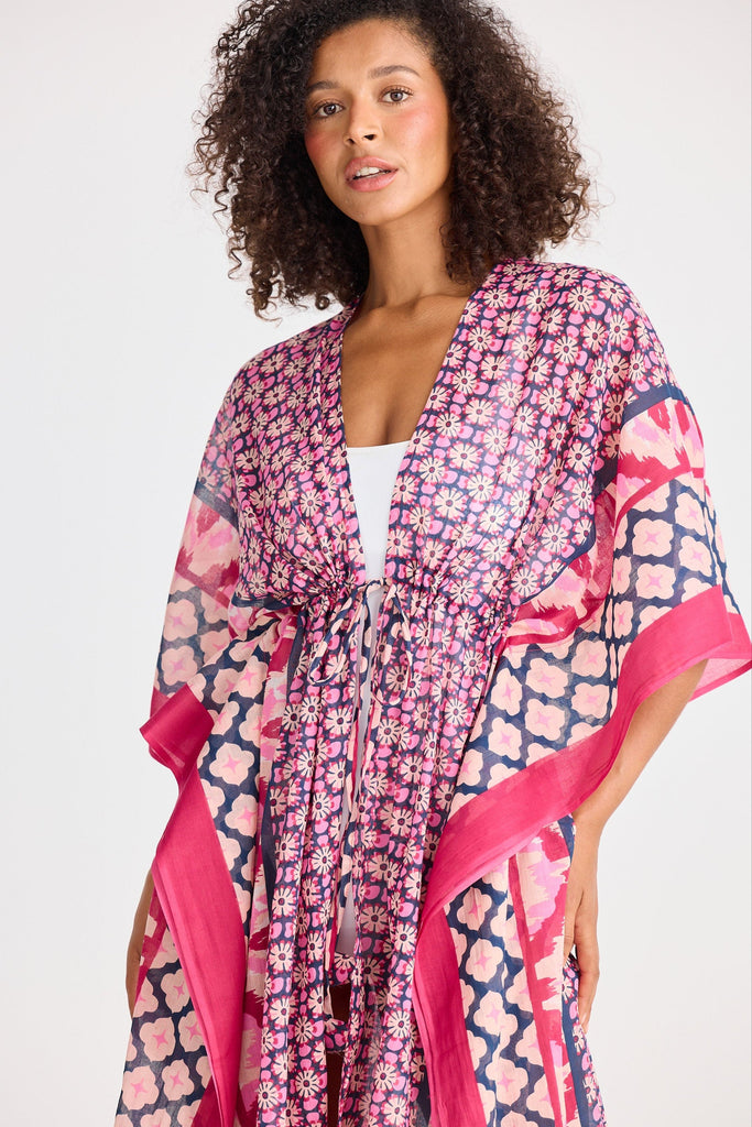Woman wearing a pink and blue patterned kimono against a white background