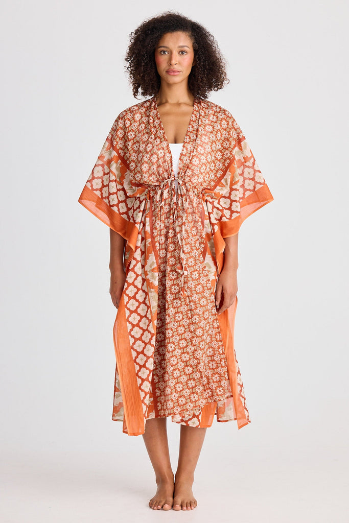 Woman wearing an orange patterned kaftan on a white background