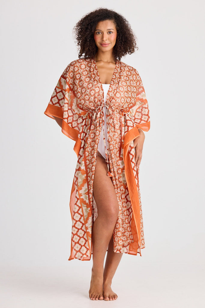 Woman wearing an orange and white patterned kaftan on a white background