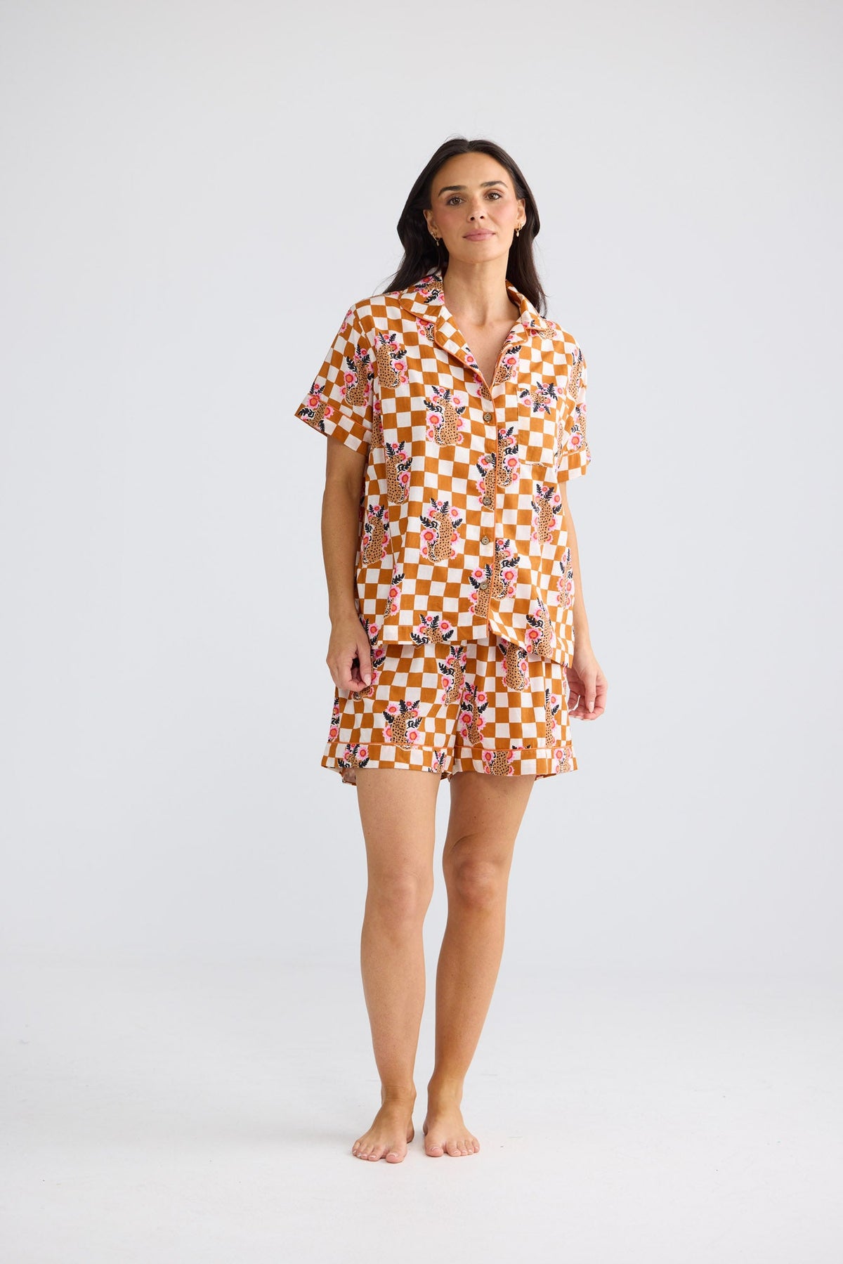 Model wearing Namaste Pyjama Set in tiger check: short-sleeve button-up shirt and shorts in a checkerboard print.
