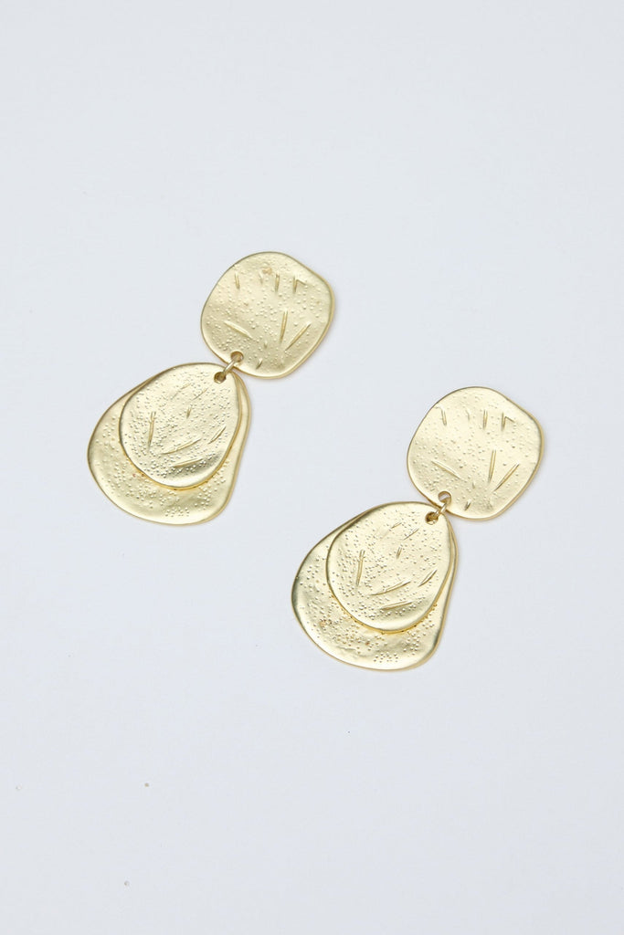 Gold earrings on a light gray background