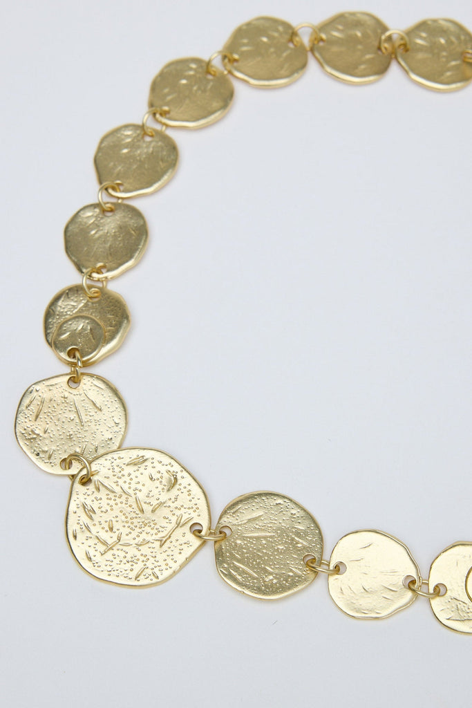 Gold necklace with circular pendants on a light gray background