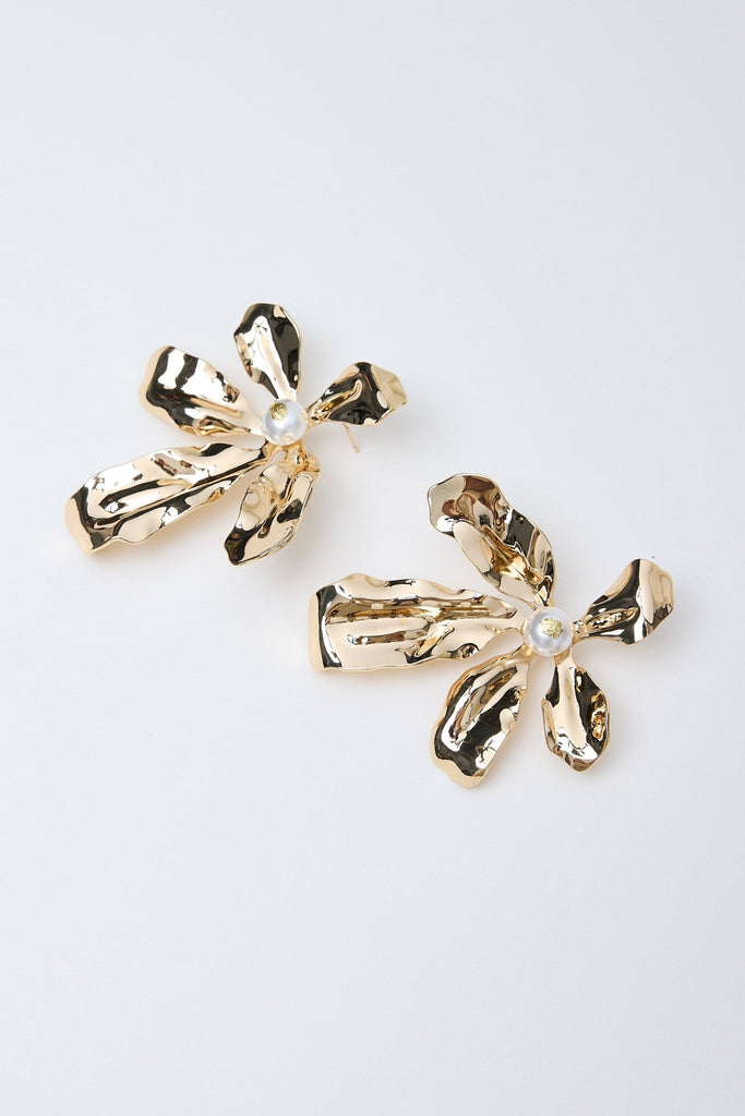 Gold flower-shaped earrings on a light gray background
