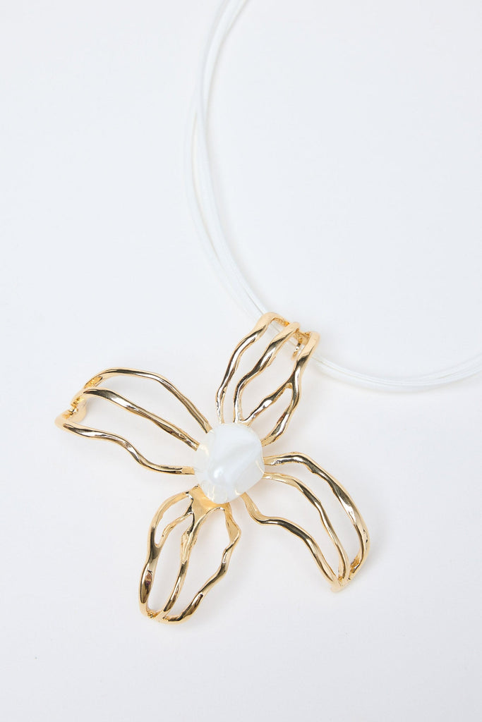 Gold flower-shaped pendant with a pearl on a white background