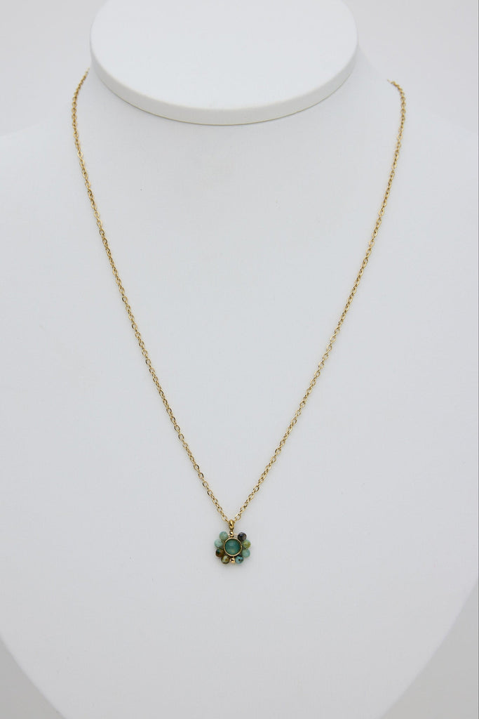 Gold necklace with a green pendant on a white mannequin bust