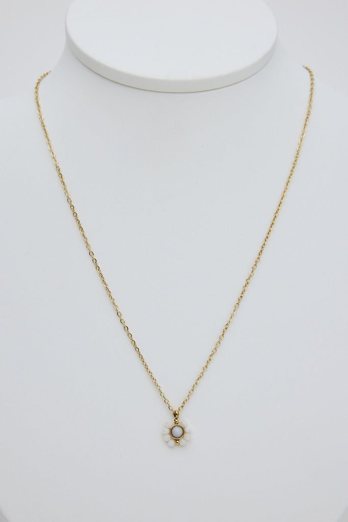 Gold necklace with a small pendant on a white mannequin bust