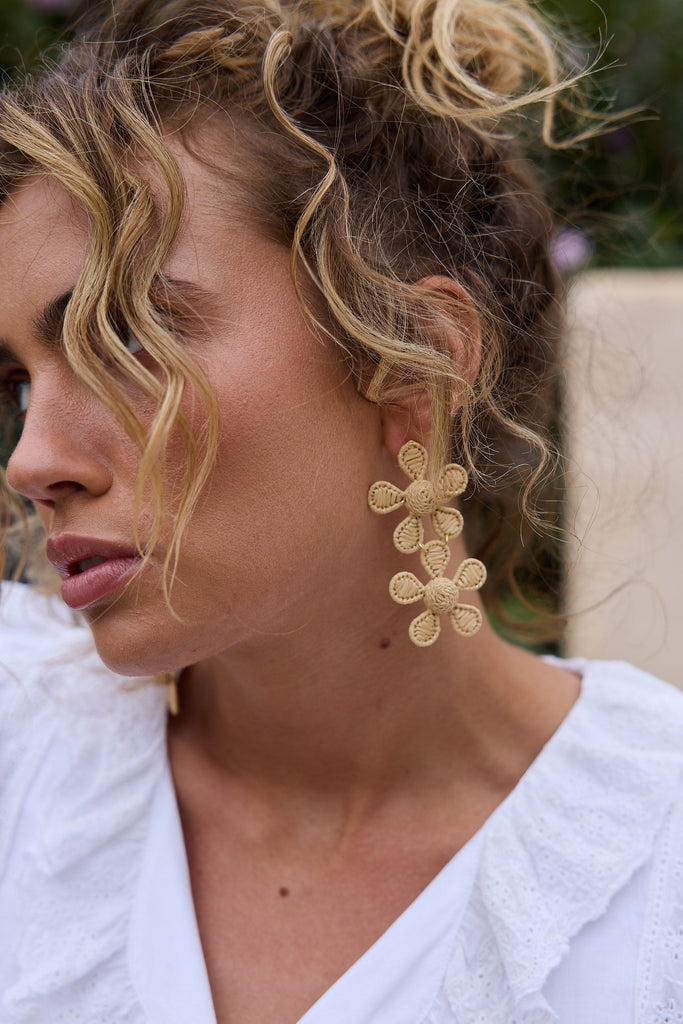 Woman wearing natural floral earrings with a blurred background