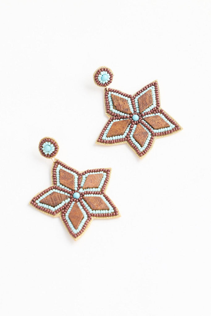 Pair of flower-shaped earrings with turquoise stones on a white background