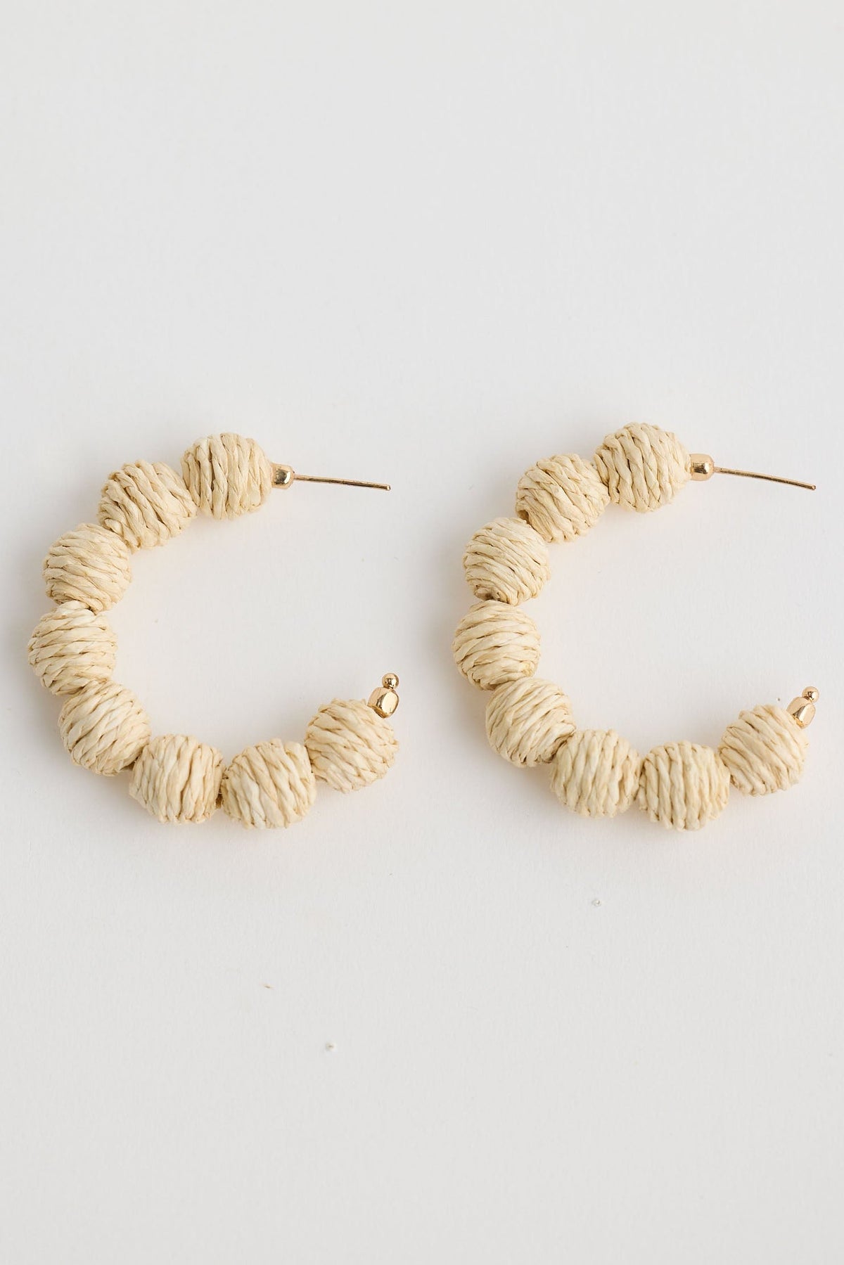 Pair of beige hoop earrings on a light gray background