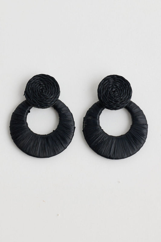 Pair of black raffia earrings on a light gray background