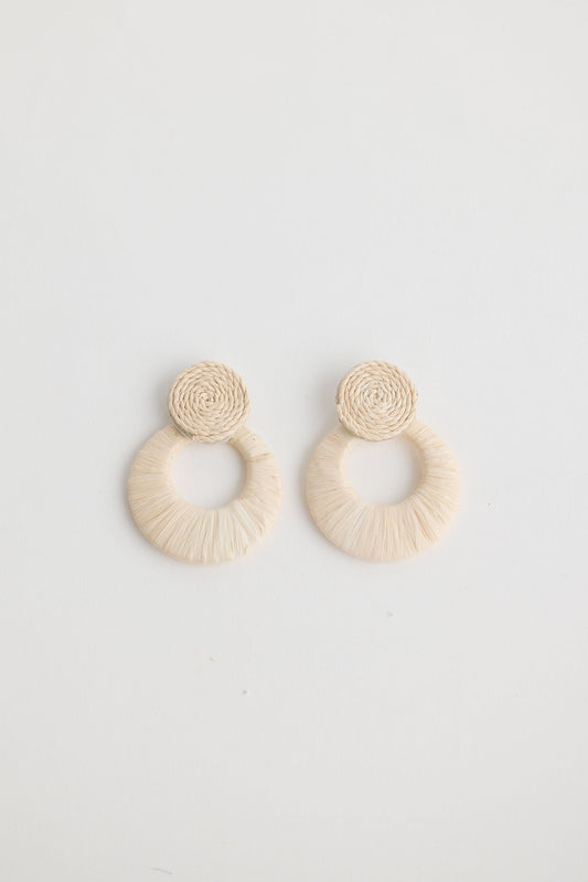 Pair of beige raffia hoop earrings on a light gray background