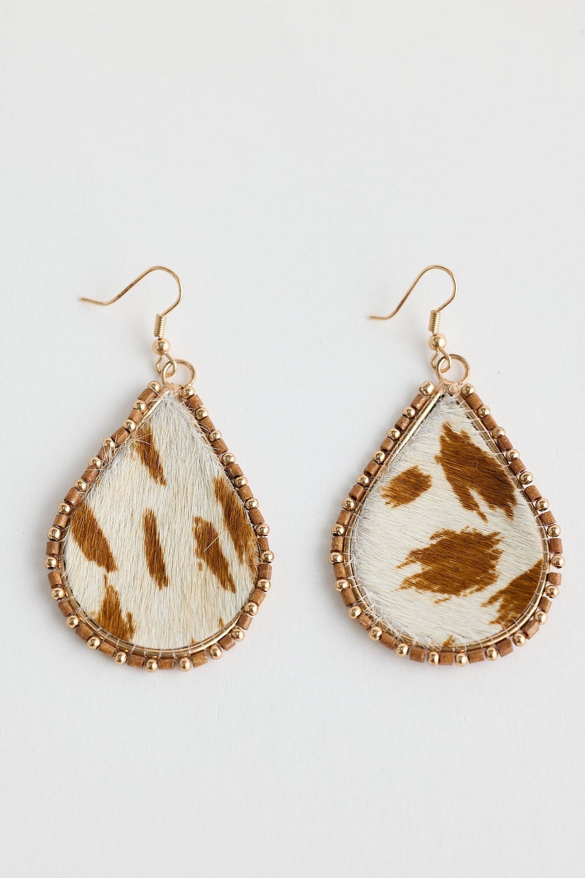 Teardrop-shaped earrings with brown and white pattern on a light gray background