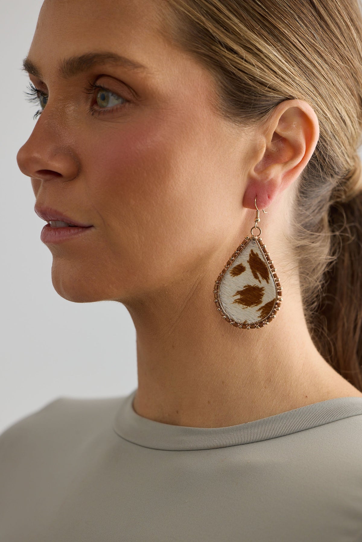 Close-up of a woman wearing a decorative earring with a neutral background
