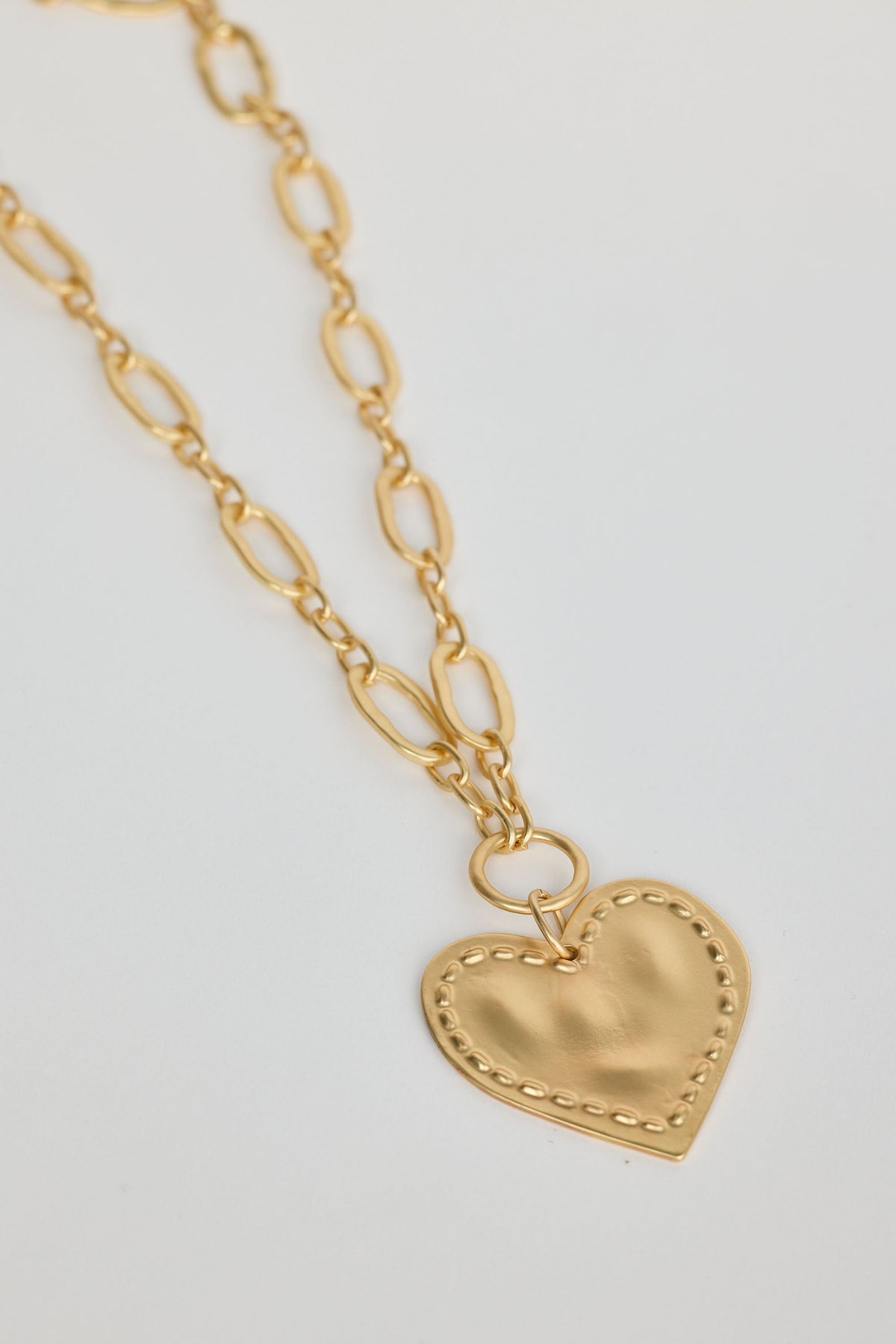 Gold heart-shaped pendant necklace on a light gray background