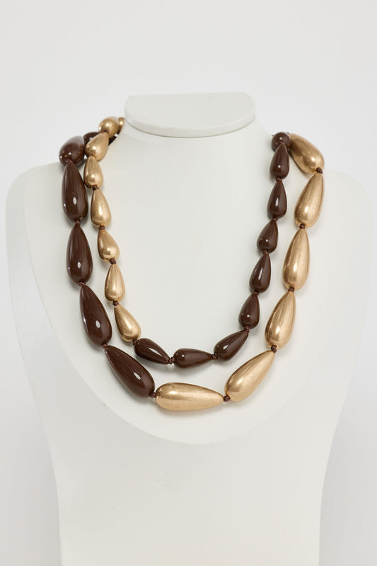 Necklace with brown and gold beads on a mannequin against a white background