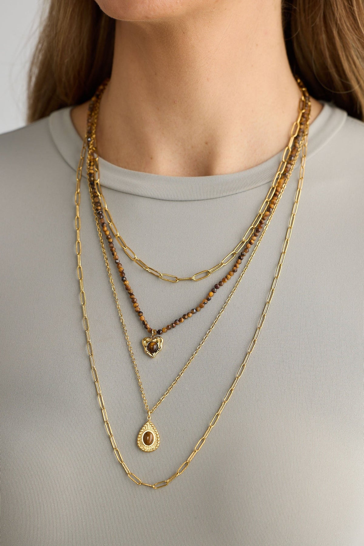 Layered gold necklaces on a plain background
