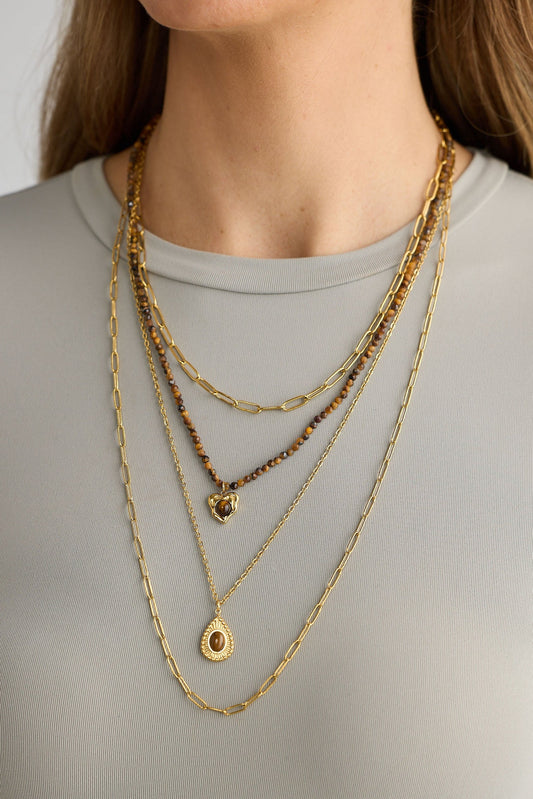 Layered gold necklaces on a plain background
