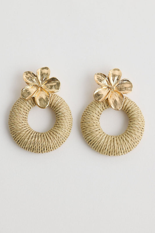 Pair of gold hoop earrings with floral tops on a light gray background