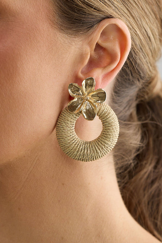 Woman wearing a gold hoop earring against a neutral background