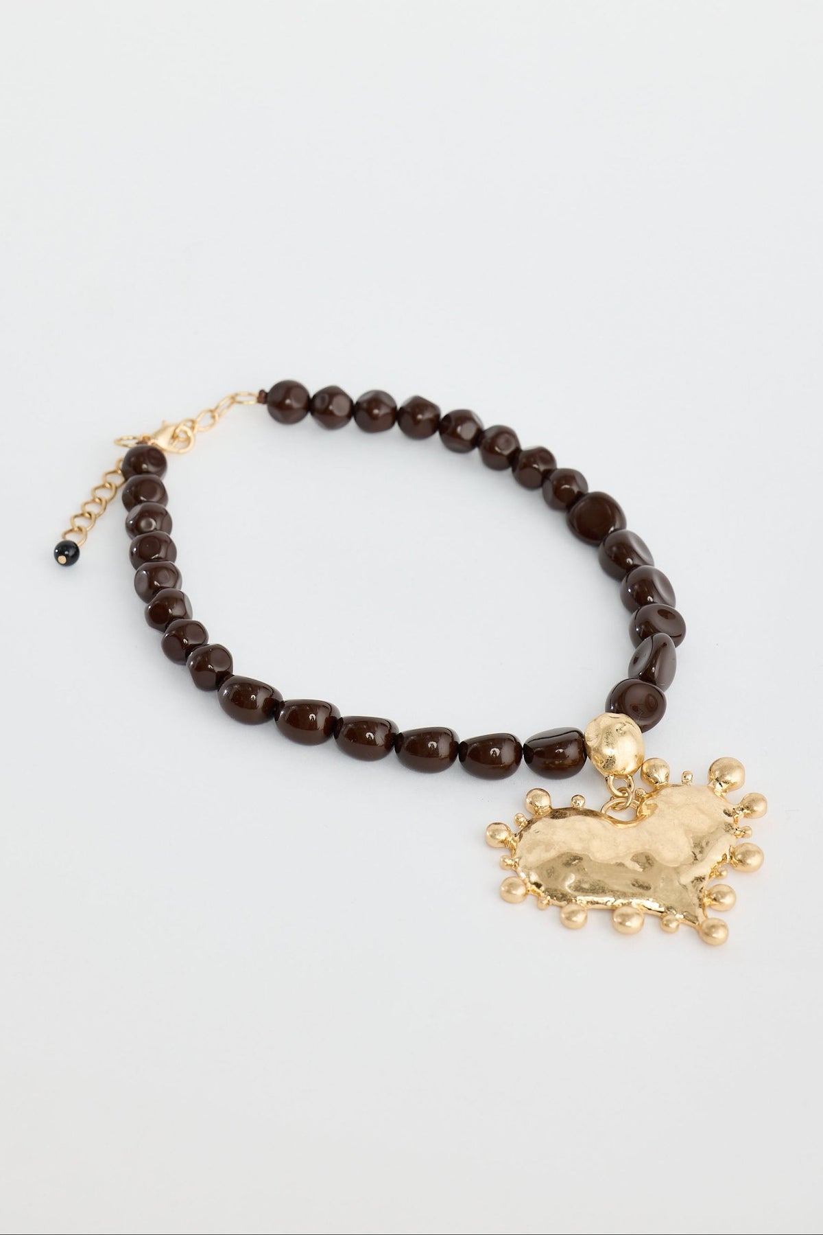 Necklace with brown beads and gold charm on a light gray background