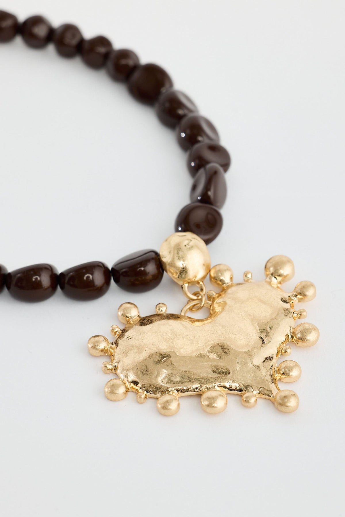 Necklace with brown beads and a gold horse charm on a light gray background