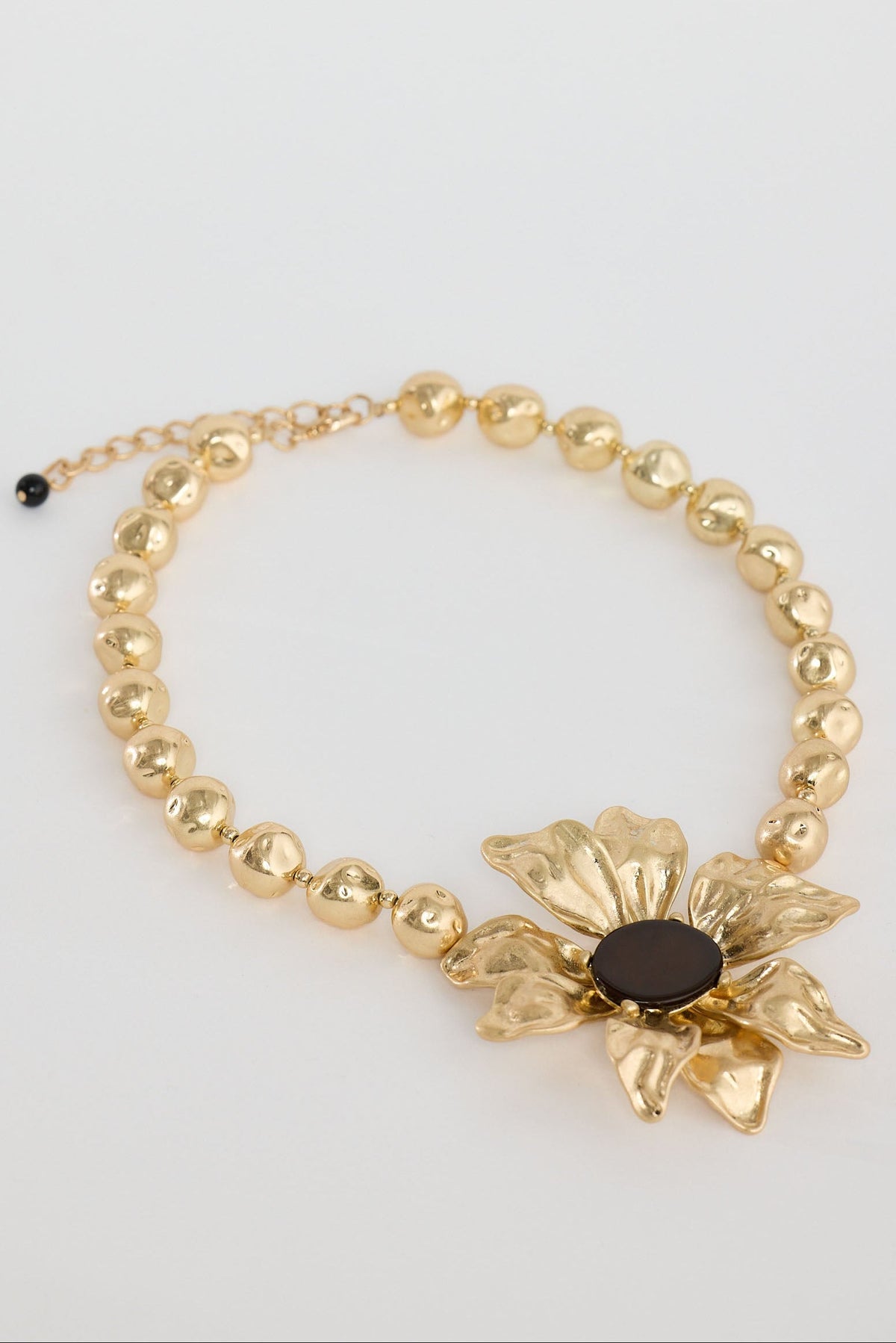 Gold bracelet with a floral design on a light gray background