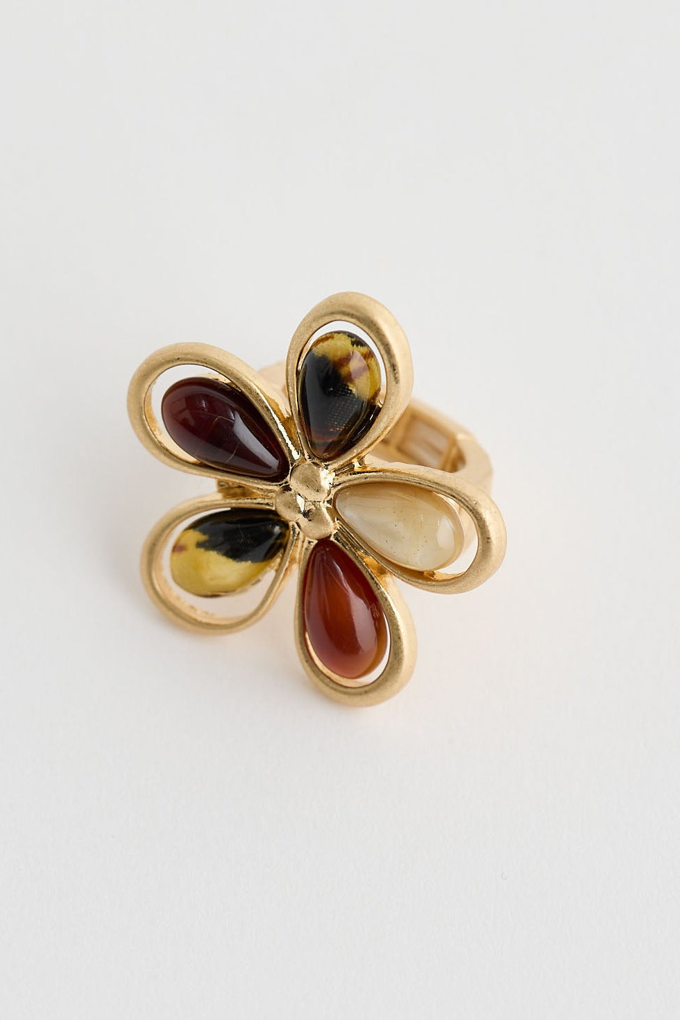Gold flower-shaped ring with colored stones on a white background
